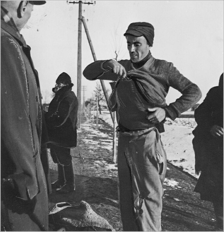 A Jewish laborer from the Radom ghetto is forced to show a German guard what is concealed beneath his sweater